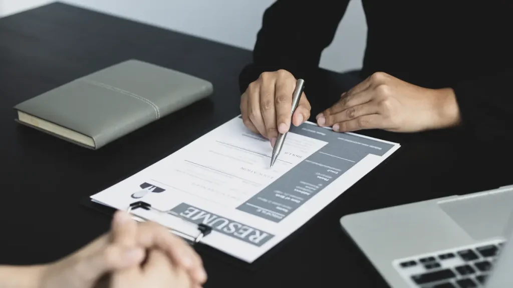 Seorang profesional muda Indonesia sedang berlatih interview bahasa Inggris di depan laptop dengan ekspresi percaya diri, didampingi seorang tutor online.